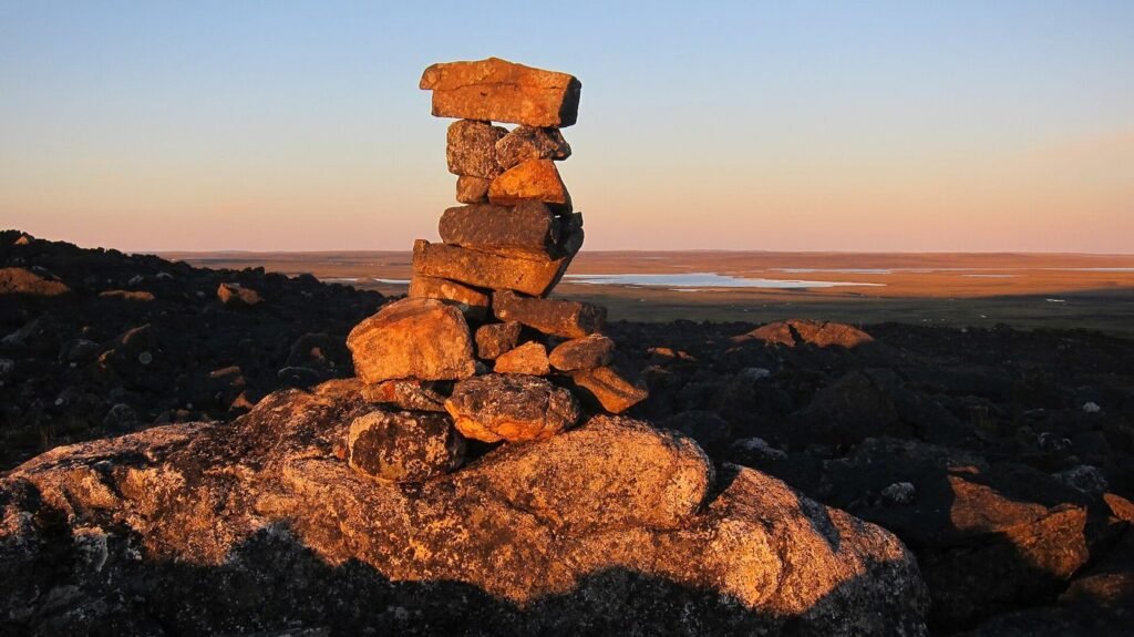 Inukshuk de pierres sur la toundra au coucher du soleil